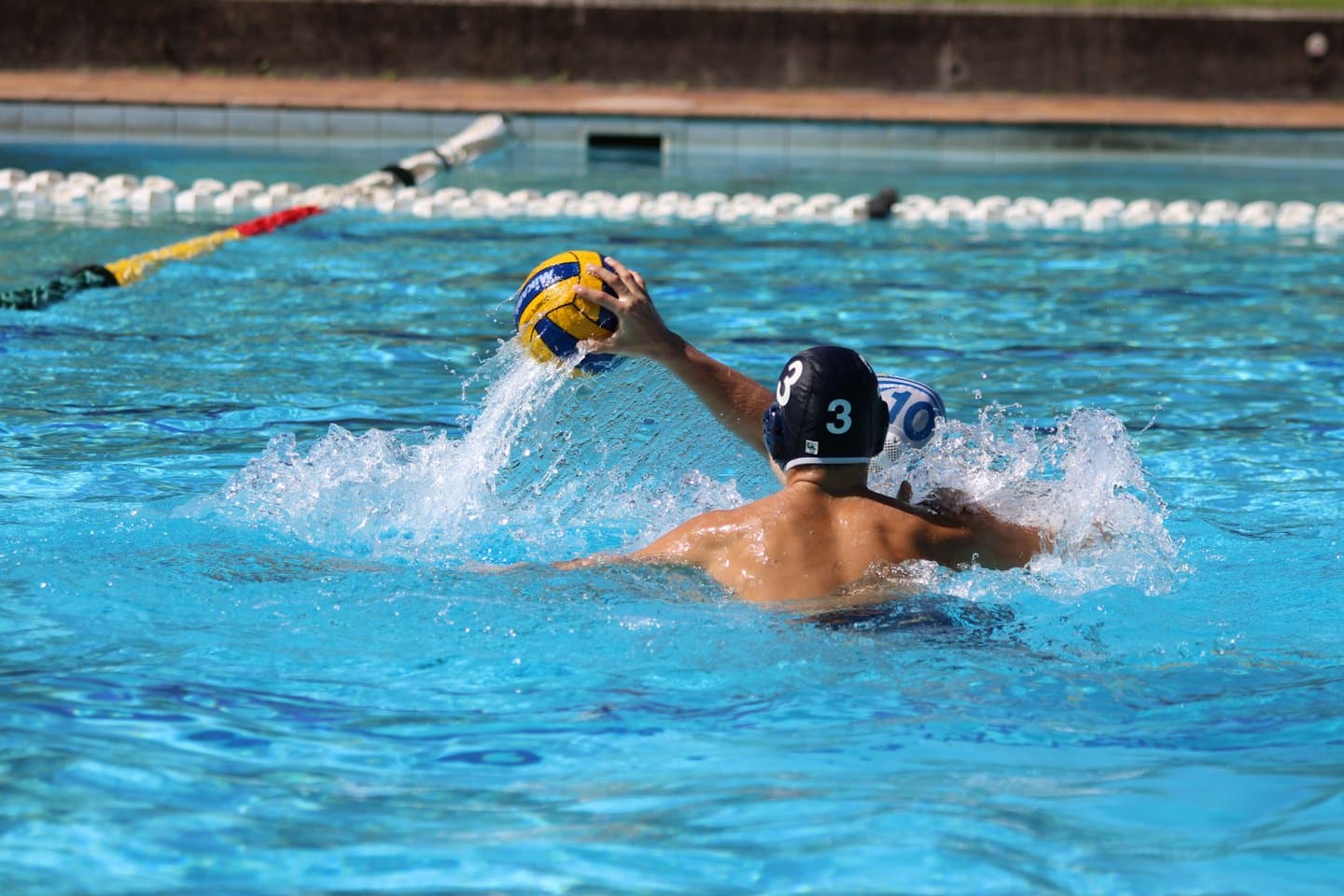 Hráči vodného póla sa počas zápasu striekajú v bazéne.